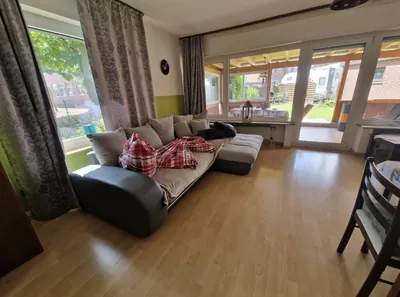 Wohnung 3, Wohnzimmer mit Sofa und Fenstern zur Terrasse