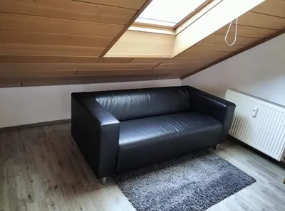 Wohnung 4, Zimmer im Dachgeschoss mit Sofa unter dem Dachfenster